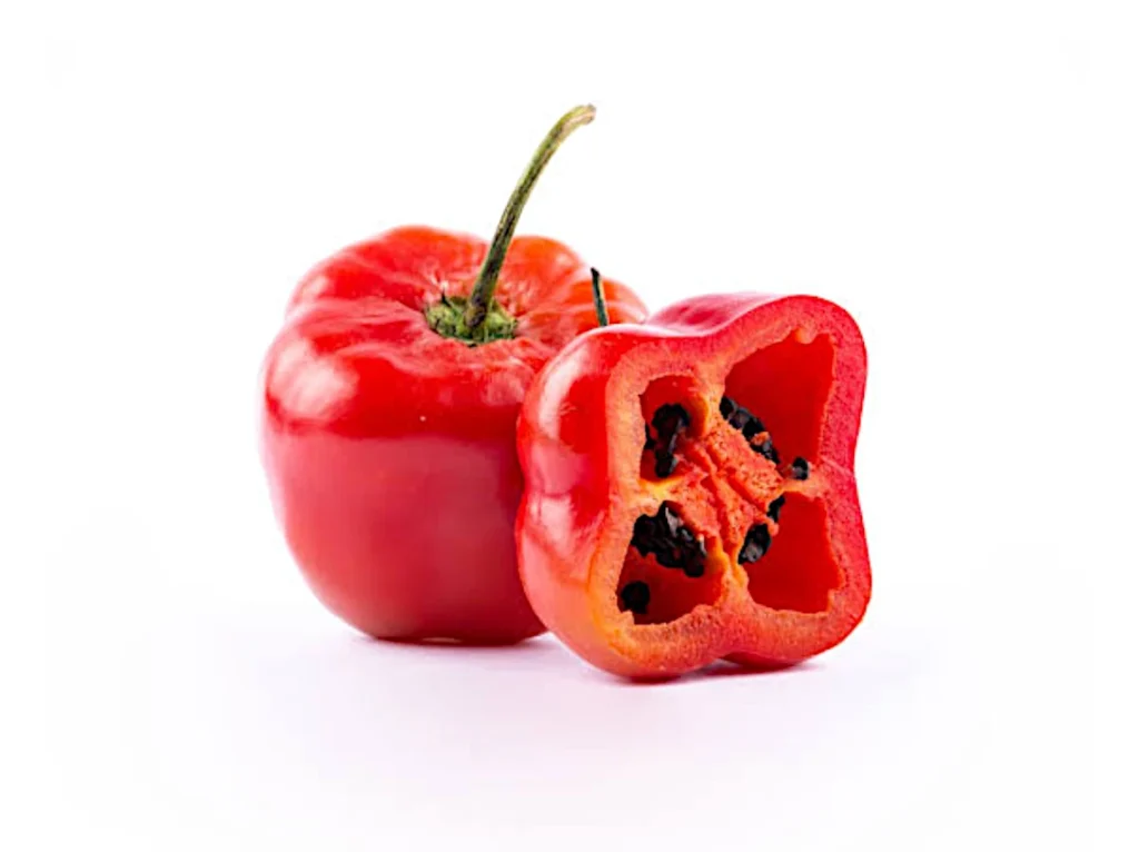Hele rocoto en een doormidden gesneden rocoto met zwarte zaadjes.