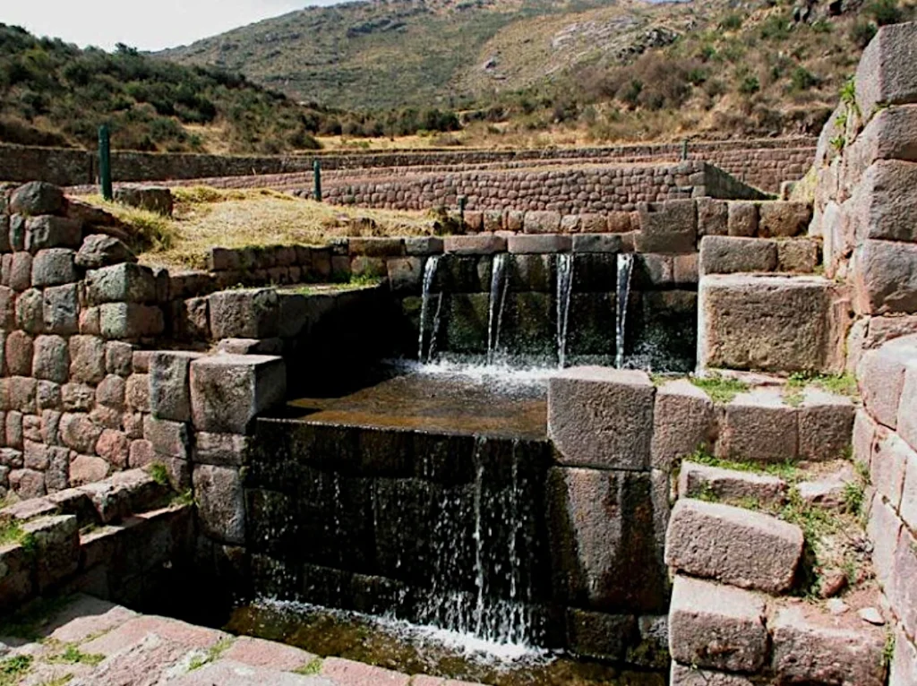 In steen gebeiteld waterkanaal met watervallen en terrassen op de archeologische vindplaats Tipón, Cusco.