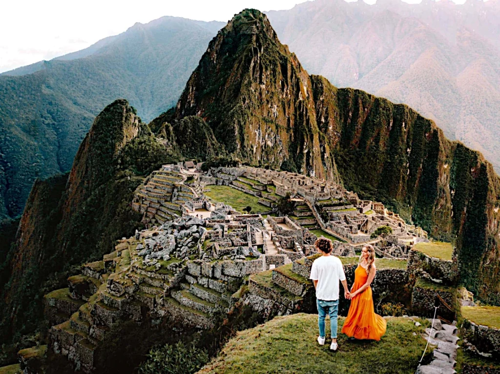 Een stel hand in hand voor de ruïnes van Machu Picchu, met de Huayna Picchu op de achtergrond.